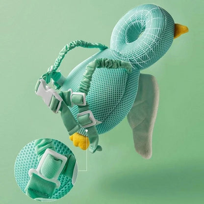 Soft teal duck-shaped baby head support with adjustable buckle straps on green background
